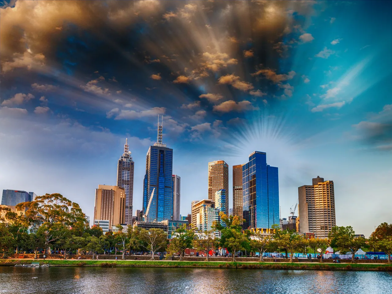 City skyline reflected in water beneath a dramatic sky